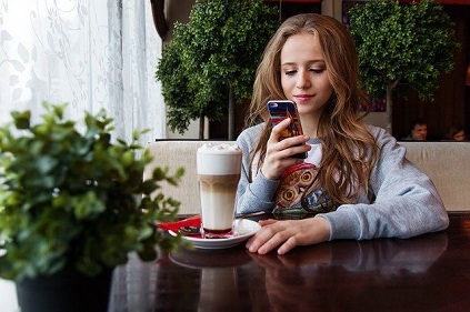adolescente en cafetería mirando el móvil
