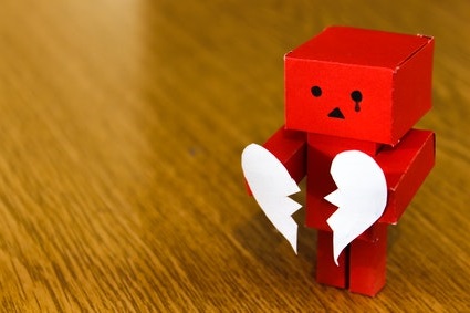 muñeco de cartón sujetando corazón de papel roto
